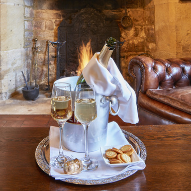 Bucket of Champagne on ice, with two filled glasses and small plate of biscuits